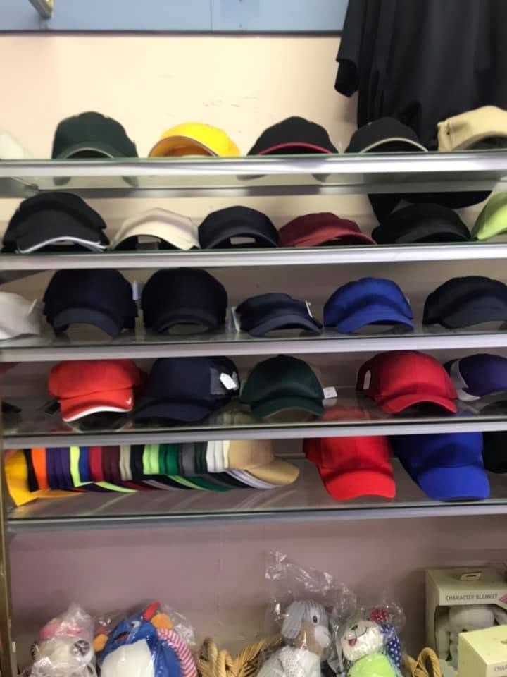 Shelves of black, navy, red, and white caps with plush toys below