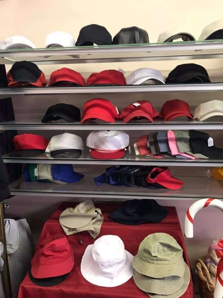 Glass shelves of caps in red, black, white, and tan, with bucket hats on the bottom shelf