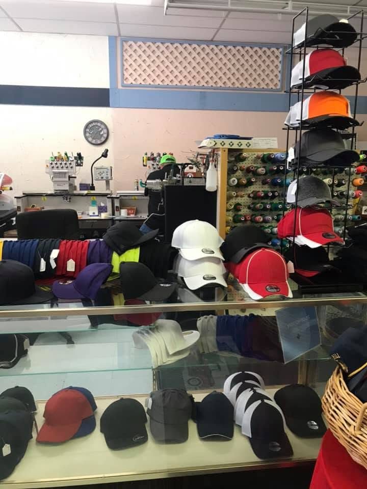 Glass counter and rack of caps in front of the embroidery machines and thread wall